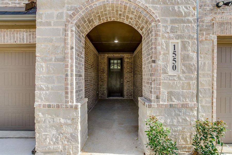 Entrance to property featuring stone siding and brick siding