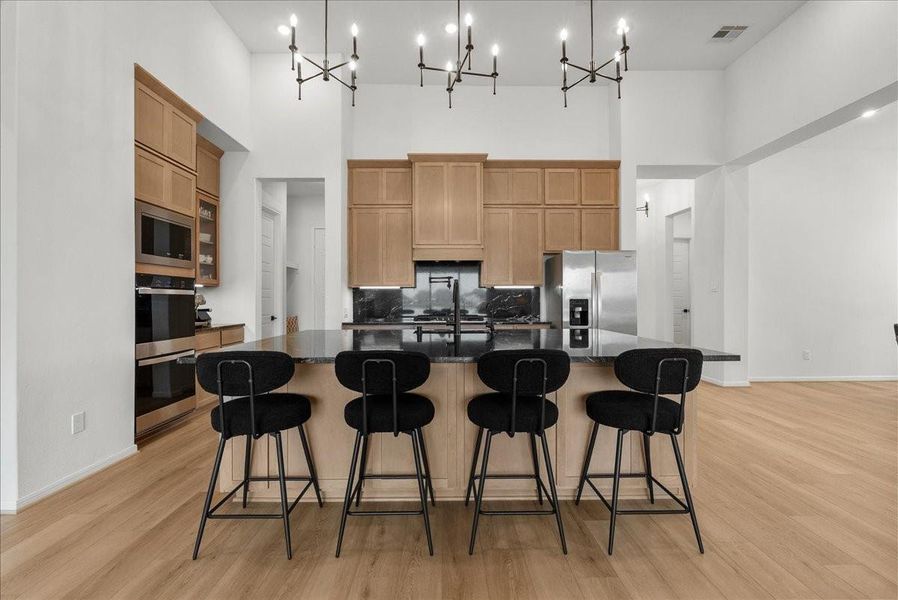 Chef’s kitchen overlooks the spacious living area and boasts double ovens, pot filler, granite countertops, designer backsplash, upgraded cabinetry, stainless steel appliances, stylish finishes, and oversized island seating.