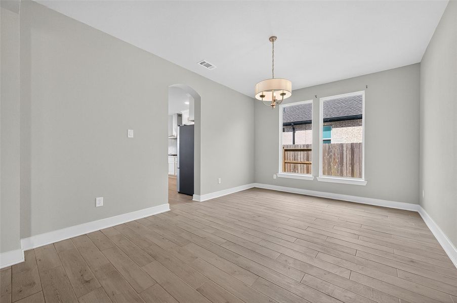 Spacious formal dining room with clean lines and contemporary lighting, perfect for intimate dinners or festive gatherings. Large windows offer backyard views and fill the space with natural light.