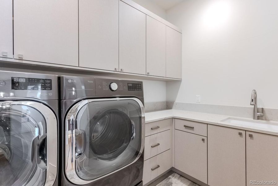 The upscale laundry room combines style and function with sleek cabinetry for organized storage, a convenient built-in sink, and a high-performance washer and dryer. Thoughtful design and premium finishes make everyday tasks feel effortless and refined.