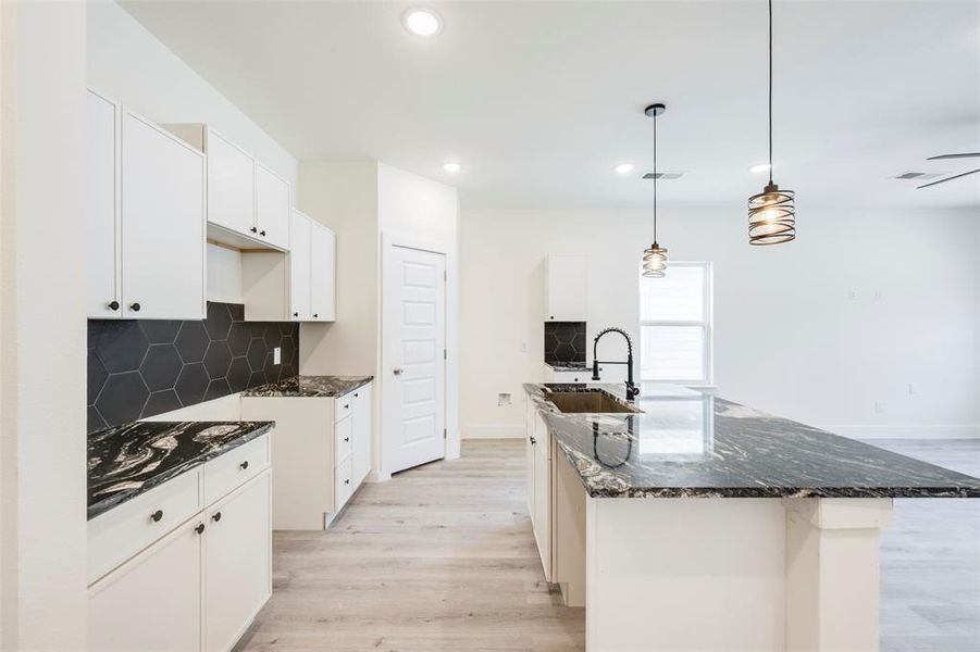 Kitchen featuring dark stone counters, backsplash, light wood-style flooring, white cabinets, and recessed lighting