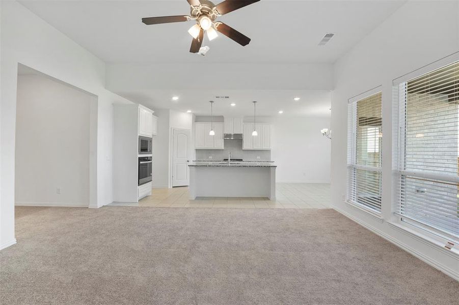 Unfurnished living room featuring ceiling fan, sink, and light colored carpet