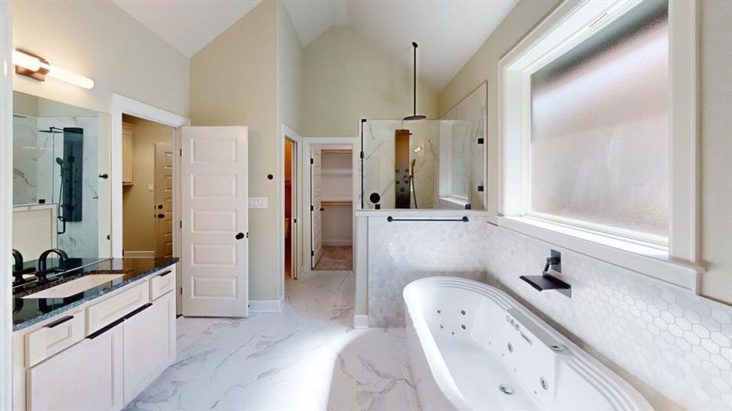 Bathroom with a marble finish shower, marble finish floors, vanity, a jetted tub, and lofted ceiling