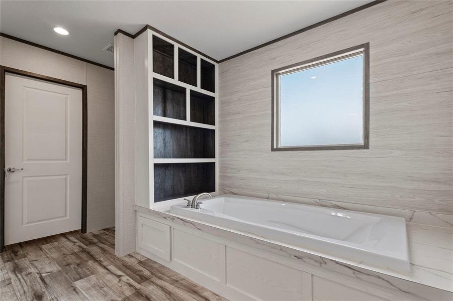 Full bathroom with a garden tub, light wood-type flooring, and crown molding