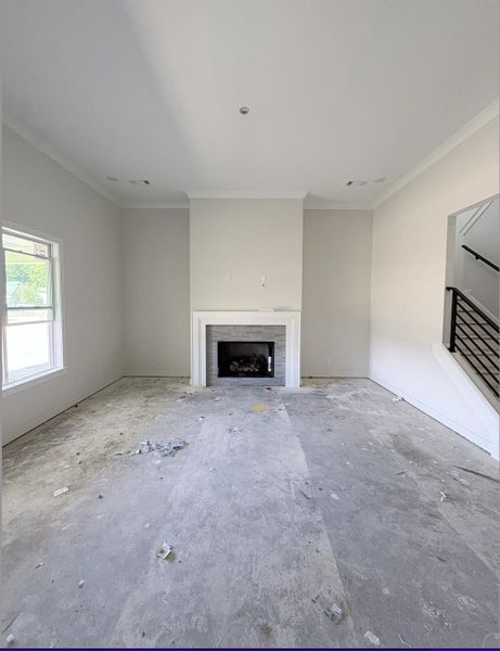 Recessed lighting, crown molding, fireplace with a tile surround, white mantel, and a black metal staircase railing Recessed lighting, crown molding, fireplace with a tile surround, white mantel, and a black metal staircase railing