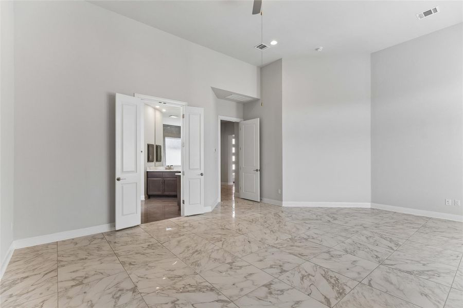 Marble-look tile flooring gleams in this open, airy primary bedroom.