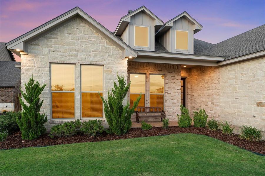 Front exterior at dusk with stone and brick facade and exterior lighting. Front exterior at dusk with stone and brick facade and exterior lighting.