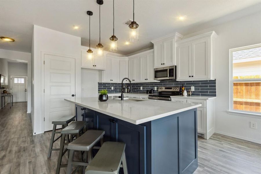 Kitchen featuring light hardwood / wood-style floors, decorative backsplash, and stainless steel appliances