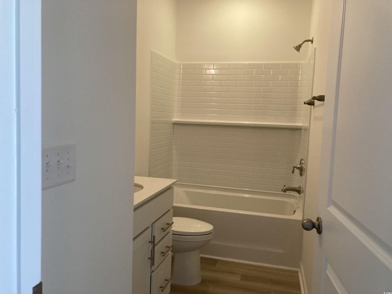 Full bathroom featuring dark wood-type flooring, vanity, and bathtub / shower combination