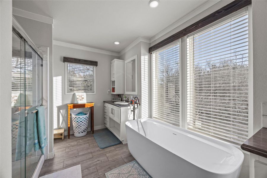 Full bathroom with vanity, a soaking tub, a shower stall, crown molding, and wood tiled floors