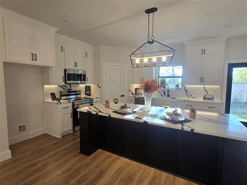 Kitchen with dark cabinetry, white cabinetry, stainless steel appliances, pendant lighting, and recessed lighting