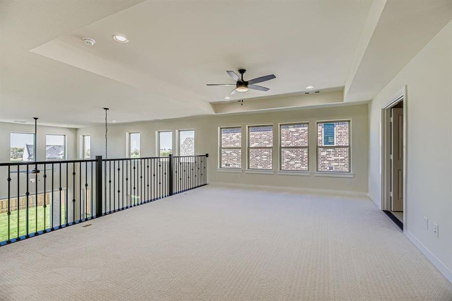 Empty room with a raised ceiling, carpet floors, recessed lighting, and ceiling fan