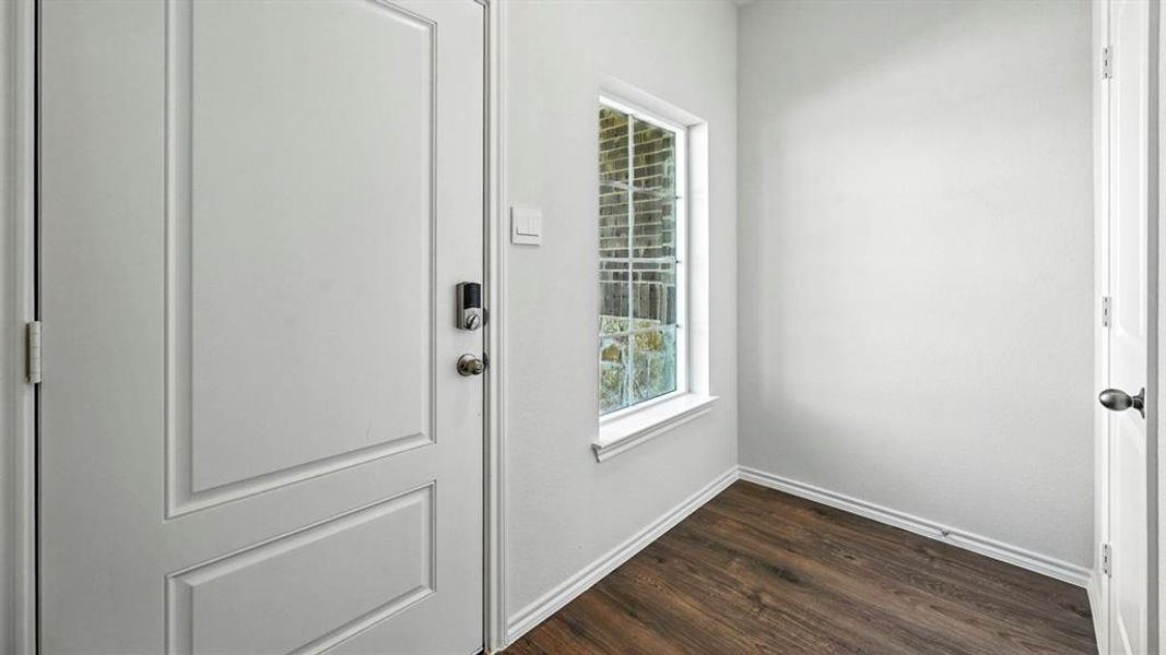 Entryway featuring a white paneled door with smart lock hardware, wood-finish flooring, white baseboards, and a window with natural light