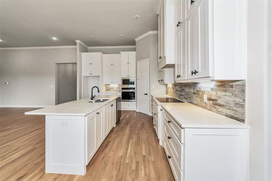 Kitchen featuring white cabinetry, stainless steel appliances, crown molding, sink, and light hardwood / wood-style floors