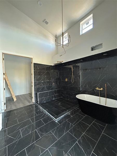 Full bathroom featuring tile walls, a freestanding bath, dark marble finish floors, a marble finish shower, and wainscoting