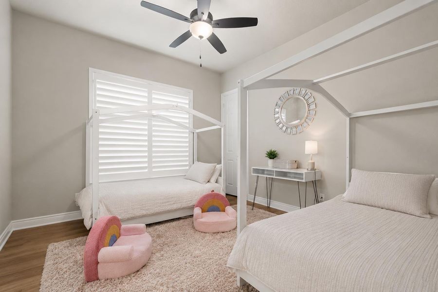 A well-lit bedroom featuring wood flooring and a modern ceiling fan, creating a comfortable living space. A well-lit bedroom featuring wood flooring and a modern ceiling fan, creating a comfortable living space.
