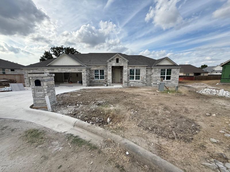 View of front of house featuring stone siding, driveway, a garage, and a shingled roof