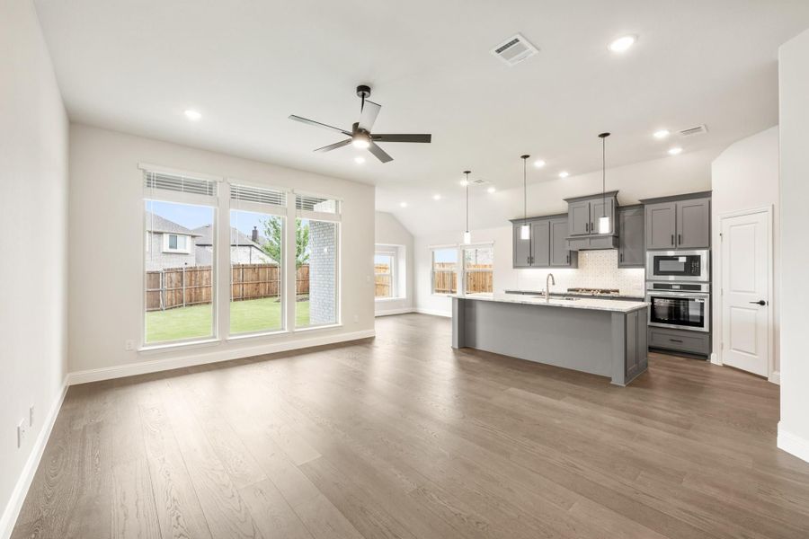 Open living area and kitchen with gray cabinets, large island, hardwood floors, and ceiling fan Open living area and kitchen with gray cabinets, large island, hardwood floors, and ceiling fan