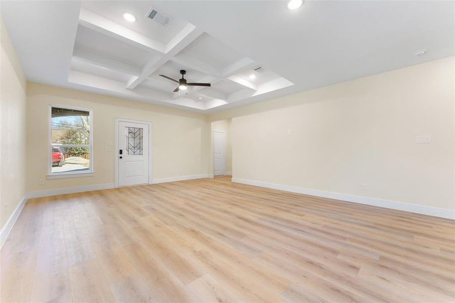 Empty room featuring beamed ceiling, coffered ceiling, ceiling fan, and light hardwood / wood-style flooring