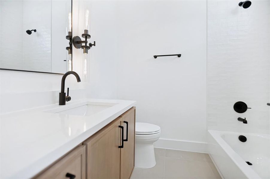 Bathroom featuring a wood-finish vanity with white countertop and integrated sink, matte black faucet, and coordinating wall sconce