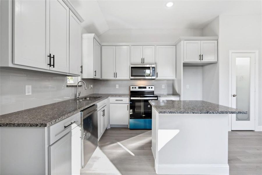 Kitchen featuring sink, light hardwood / wood-style flooring, appliances with stainless steel finishes, a kitchen island, and white cabinetry