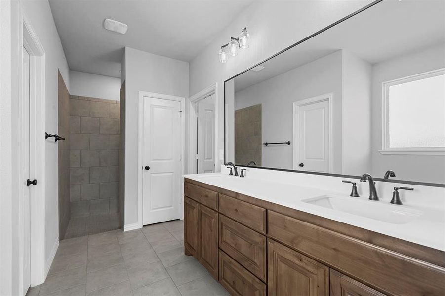 Bathroom featuring tile patterned floors, a tile shower, and vanity