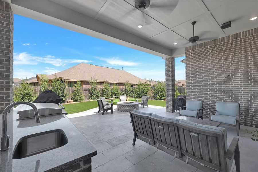 Beautiful outdoor kitchen featuring a built-in grill, sink, ample counter space, and dedicated space for a Big Green Egg, creating the perfect setup for outdoor cooking and entertaining