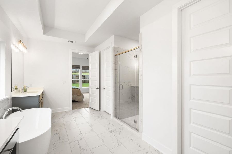 Luxurious primary bathroom retreat featuring a free-standing tub, separate shower, and elegant tile flooring.