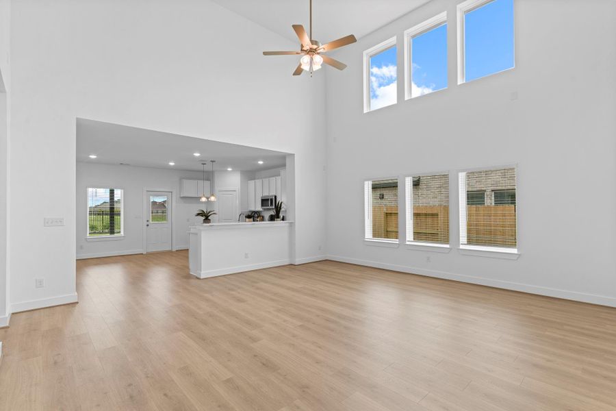 The open-concept family room is a showstopper with its towering ceilings, large windows that flood the space with natural light, and expansive layout—ideal for entertaining or everyday living. **Image Representative of Plan Only and May Vary as Built**.