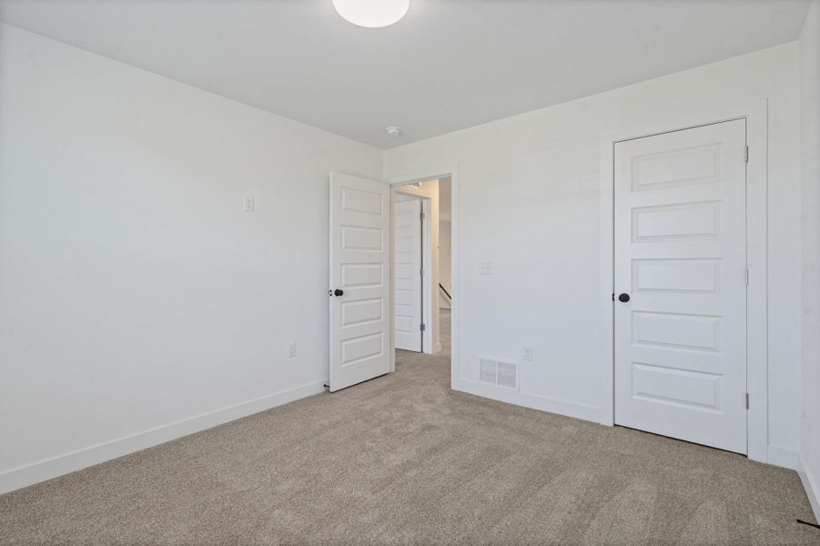 Neutral tone wall finish, plush carpet flooring, recessed ceiling light fixture, panel interior doors, and matte black door hardware Neutral tone wall finish, plush carpet flooring, recessed ceiling light fixture, panel interior doors, and matte black door hardware