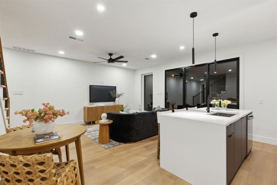 Kitchen with visible vents, a kitchen island with sink, a sink, light wood-style floors, and modern cabinets