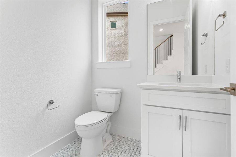 Bathroom with toilet, tile patterned floors, and vanity