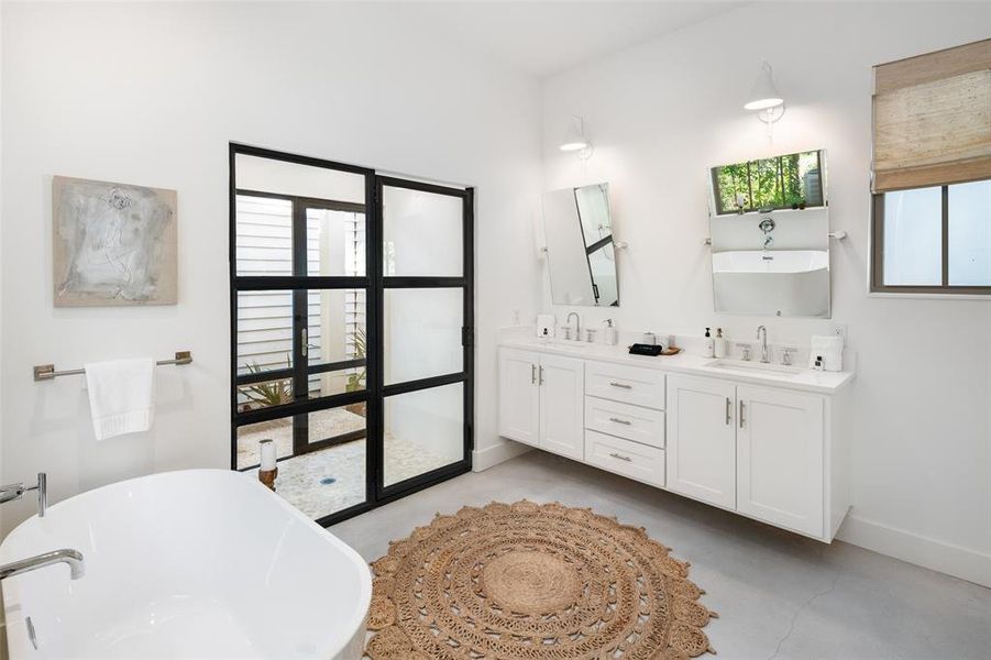 Bathroom featuring vanity, plenty of natural light, concrete floors, and a bathtub Bathroom featuring vanity, plenty of natural light, concrete floors, and a bathtub