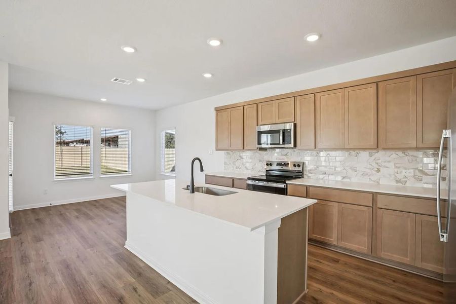 A well-lit kitchen boasts ample counter space, a central island, and modern appliances, flowing seamlessly into the adjacent living area. A well-lit kitchen boasts ample counter space, a central island, and modern appliances, flowing seamlessly into the adjacent living area.
