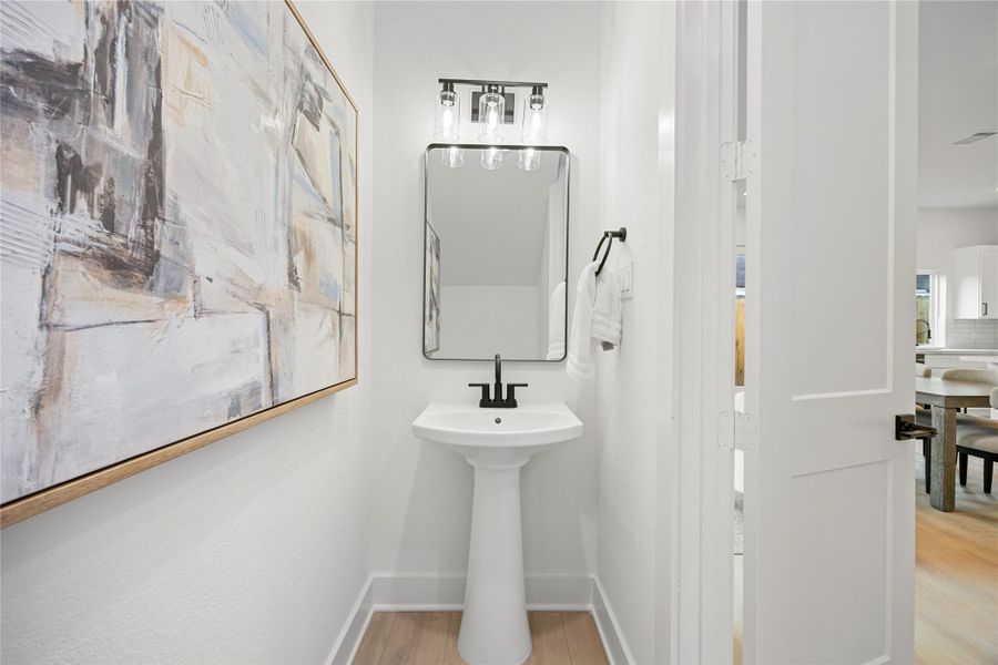 The powder room on the first floor includes a pedestal sink, mirror, dark sleek and modern fixtures--all to conveniently meet your needs. The powder room on the first floor includes a pedestal sink, mirror, dark sleek and modern fixtures--all to conveniently meet your needs.