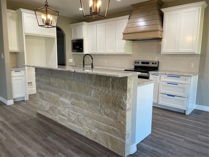 Kitchen with range, ventilation hood, a chandelier, dark wood-style floors, and white cabinets