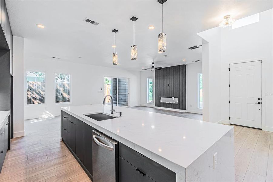 Kitchen with a center island with sink, pendant lighting, light stone countertops, plenty of natural light, and recessed lighting