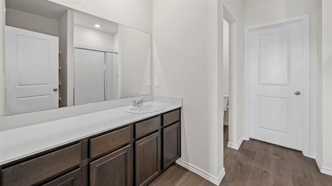 Vanity with dark wood-finish cabinetry, white countertop, and integrated sink