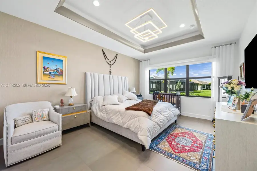 Bedroom featuring a double-tiered tray ceiling, modern geometric LED pendant lighting, recessed lighting, and large-format tile flooring