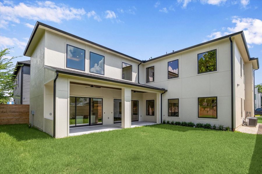 Expansive backyard with covered patio and large windows overlooking the lawn. Expansive backyard with covered patio and large windows overlooking the lawn.