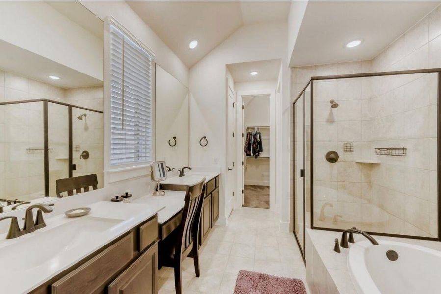 Bathroom with a stall shower, a bath, vaulted ceiling, vanity, and a walk in closet