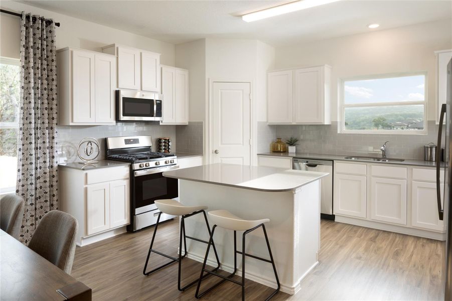 Kitchen with healthy amount of natural light, appliances with stainless steel finishes, and white cabinetry