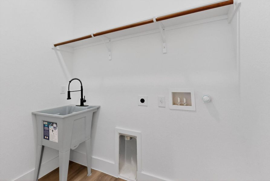 Functional laundry space featuring a utility sink and convenient hanging rod for garments.