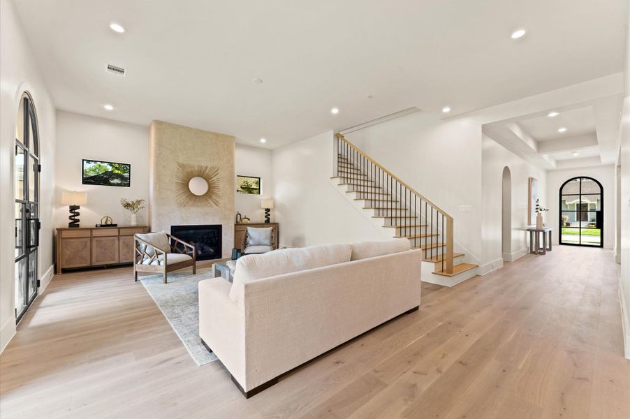 Spacious living area with view of arched steel front door. Contemporary staircase with iron balusters adds a stylish touch. Spacious living area with view of arched steel front door. Contemporary staircase with iron balusters adds a stylish touch.