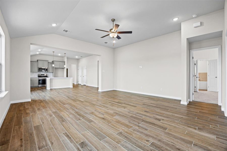 Gleaming wood-look tile floors run through the open living space under a vaulted ceiling. Gleaming wood-look tile floors run through the open living space under a vaulted ceiling.