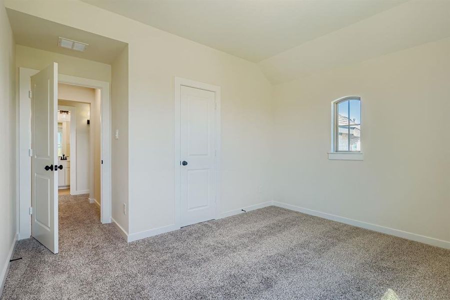Unfurnished bedroom featuring light colored carpet, lofted ceiling, and a closet