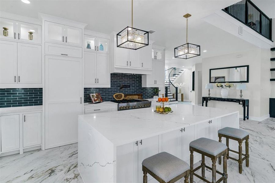 Kitchen featuring a center island, pendant lighting, white cabinetry, light stone counters, and tasteful backsplash