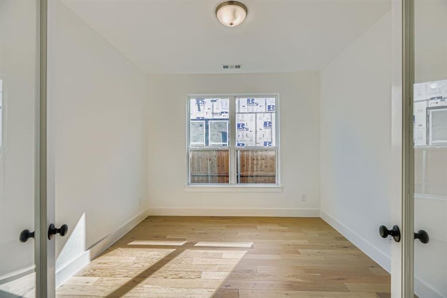 Spare room featuring light wood finished floors and french doors Spare room featuring light wood finished floors and french doors