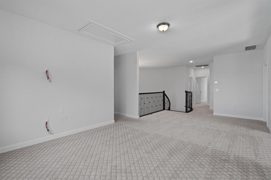 Empty room featuring carpet floors and attic access Empty room featuring carpet floors and attic access