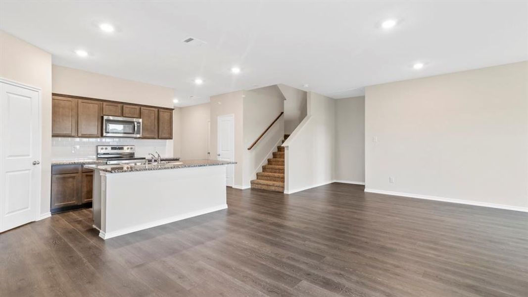 Open-concept living space with dark wood-finish flooring, recessed lighting, and neutral wall tones